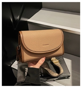 Détail du sac tressé marron avec bordure en cuir et bandoulière large à motifs géométriques