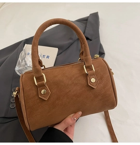 Detailed view of brown Boston bag with textured finish and golden rivet hardware