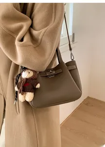 Détail du sac seau en cuir grainé marron foncé avec fermoir et breloque ours en peluche