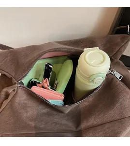 Spacious interior view of dark brown suede tote bag holding water bottle and wallet