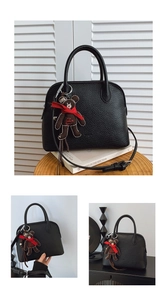 Detail of black lychee grain shell bag with cute brown teddy bear charm and strap