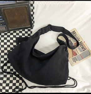 Minimalist black hobo shoulder bag with adjustable wide strap shown in a vintage setting