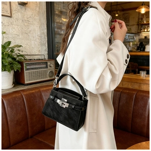 Detail of black textured leather handbag with metal turn-lock and strap closure