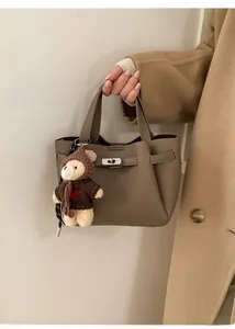 Vue détaillée du sac seau en cuir texturé avec fermoir argenté et breloque ours