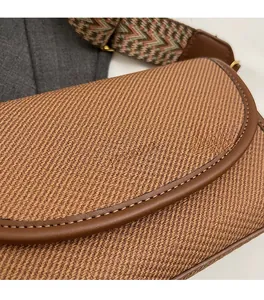 Gros plan sur un sac bandoulière en sergé marron avec bordure en cuir et sangle tissée