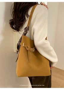 Detail of retro large capacity bucket bag with decorative scarf and metal buckle