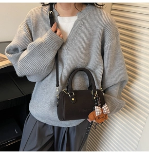 Brown Boston bag with teddy bear charm shown on a casual knitted sweater outfit