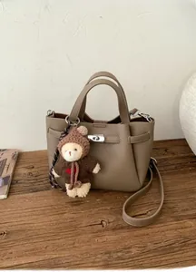Détail d'un sac seau en cuir grainé café avec fermoir argenté et breloque ourson