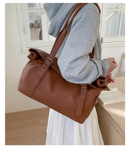 Detail of the high-quality brown pebbled leather texture and silver buckle on tote bag