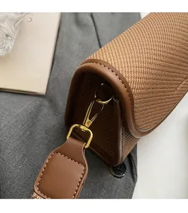 Détail du sac bandoulière marron tissé montrant la texture et la boucle dorée