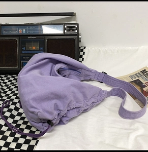 Detail of purple canvas crossbody bag with drawstring closure and retro aesthetic