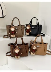 Détail d'un sac seau en cuir grainé avec fermoir rotatif en métal et pendentif ours