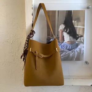 Close-up of brown suede bucket bag with decorative silk scarf and gold hardware