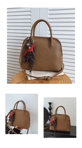 Detail of a brown lychee pattern leather shell bag with adjustable strap and bear charm