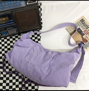 Detail of lavender canvas crossbody bag with adjustable strap and drawstring texture