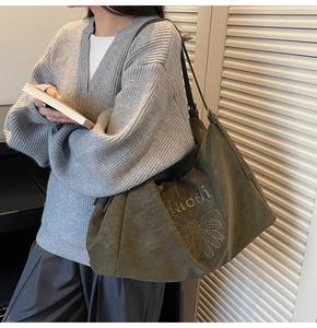 Detail of olive green suede tote bag with daisy embroidery and Maodi brand text