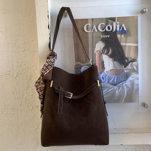 Detail of vintage coffee-brown bucket bag featuring matte texture and silk scarf detail