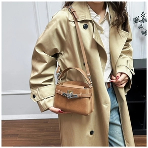 Detail of tan leather handbag with silver metallic turn-lock and detachable strap