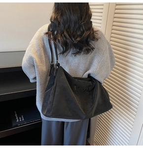 Detailed view of black suede tote bag with daisy embossing and Meodi embroidery
