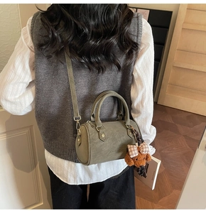 Detail of vintage olive green Boston bag with plush bear charm and adjustable strap