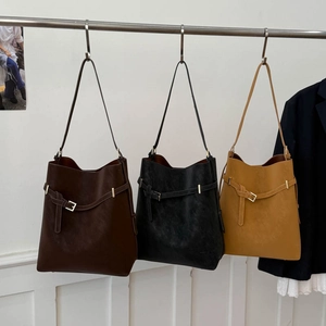 Detailed view of large tote bags in brown, black, and yellow with decorative buckle straps