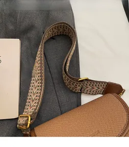 Détail du sac besace tissé marron avec large bandoulière en toile colorée et boucle dorée