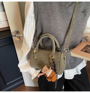 Detail of moss green mini Boston bag featuring teddy bear charm and soft matte finish