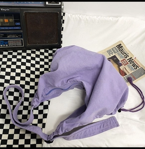 Detail of lavender canvas crossbody bag with drawstring side and wide shoulder strap