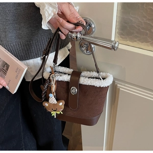 Detail der braunen Wildleder-Eimertasche mit weißem Kunstpelz und Bärenanhänger
