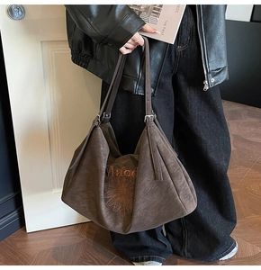 Close-up of deep brown suede tote bag with floral embroidery and adjustable strap