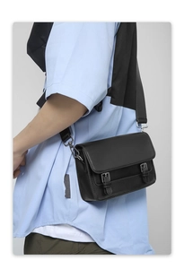 Close-up of black messenger bag featuring vintage double-buckle closure and silver hardware