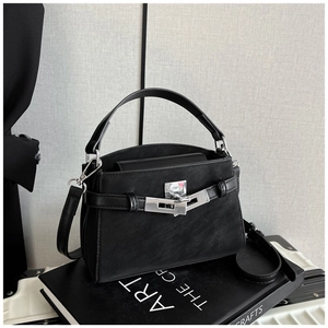 Detail of a chic black textured leather handbag with silver lock on artistic books