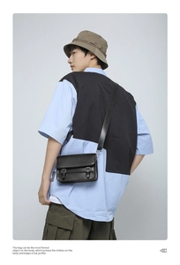 Detail of black matte leather crossbody bag featuring dual buckle closure on the flap