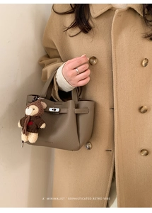 Détail du sac seau en cuir grainé avec fermoir rotatif en métal et pendentif ours mignon