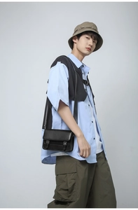 Front view of a matte black leather flap messenger bag with metallic buckle straps