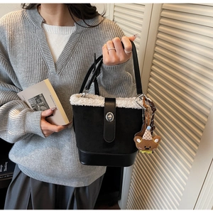Detail der Retro-Eimertasche mit weißem Kunstlammfell-Besatz und süßem Bärenanhänger