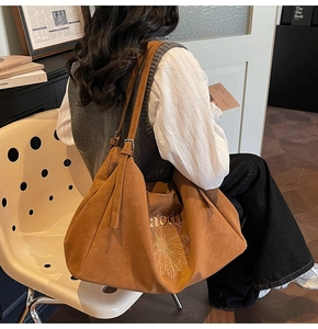 Close-up of brown suede tote bag with daisy embroidery and chic letter details