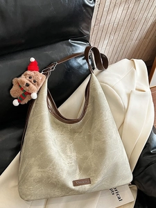 Large gray-green tote bag with brown leather straps and festive puppy charm on a sofa