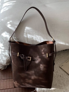 Retro dark brown matte bucket shoulder bag with gold hardware in natural light setting