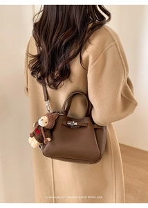 Détail d'un sac seau en cuir marron foncé avec fermoir argenté et bijou d'ours