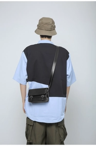 Detail of black vintage faux leather crossbody bag with dual buckle closure and long strap