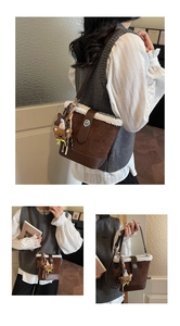 Detail einer braunen Plüsch-Beuteltasche mit weißem Lammfellbesatz und süßem Bärenanhänger