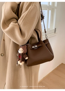 Détail du sac seau en cuir marron foncé avec fermoir argenté et breloque petit ours