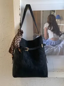 Large black suede tote bag with decorative scarf and ethnic beads on white wall