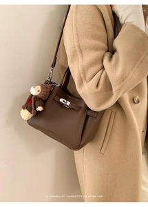 Détail du sac seau en cuir grainé marron foncé avec boucle argentée et breloque ours
