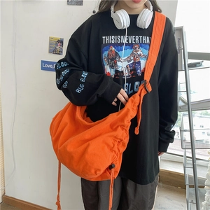 Large orange canvas crossbody bag with adjustable strap and drawstring detail