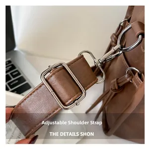 Detail of brown leather bag featuring an adjustable shoulder strap with silver buckle