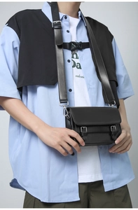 Detailed view of a black crossbody messenger bag with silver buckles and leather strap
