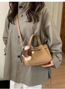 Détail du sac seau en cuir kaki avec fermoir rotatif et charmant petit ours