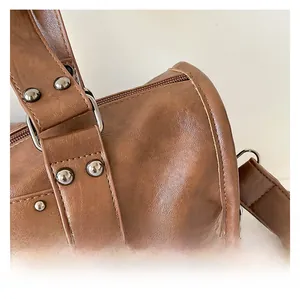 Close-up of brown litchi pattern leather bag with metal rivets and neat stitching details